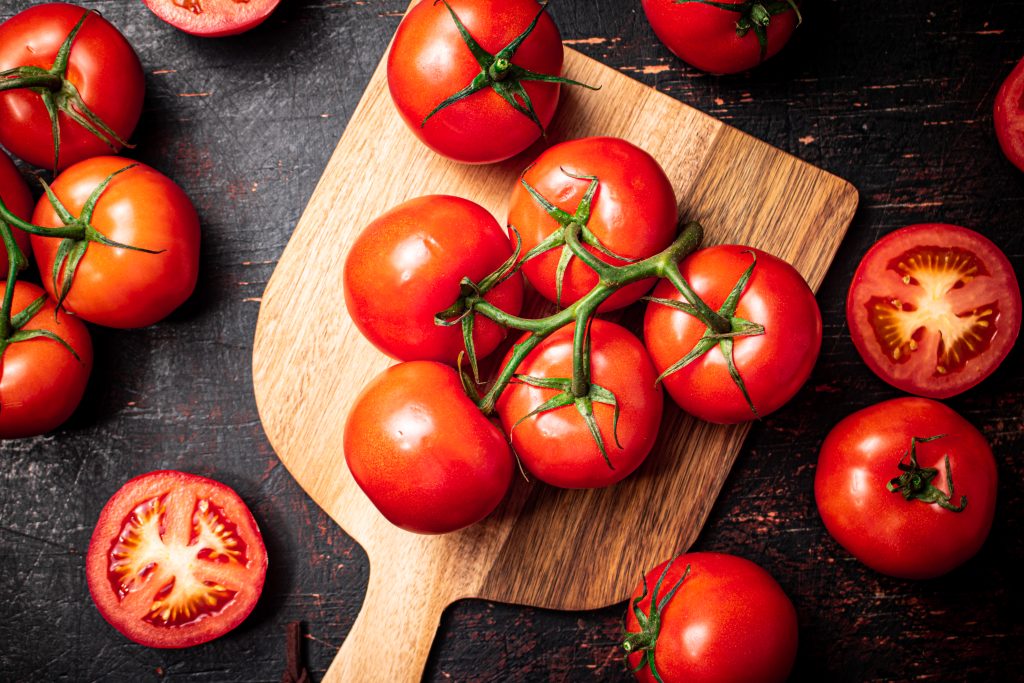 Fresh tomatoes on a wooden cutting board. Against a dark background. High quality photo