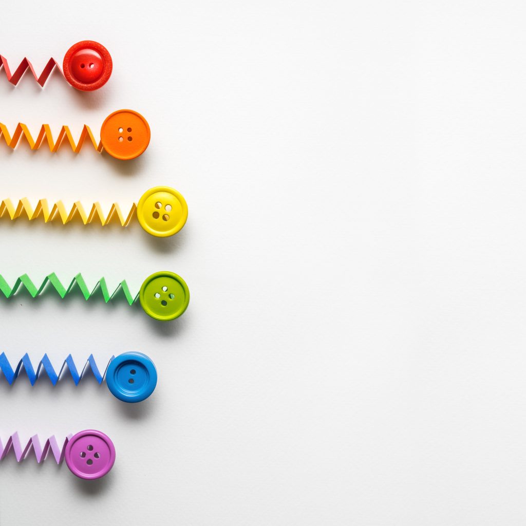 Creative concept photo of a rainbow  made of paper and buttons on grey background.