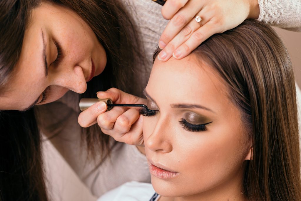 Make up artist applying eyeliner on female client's eyelids