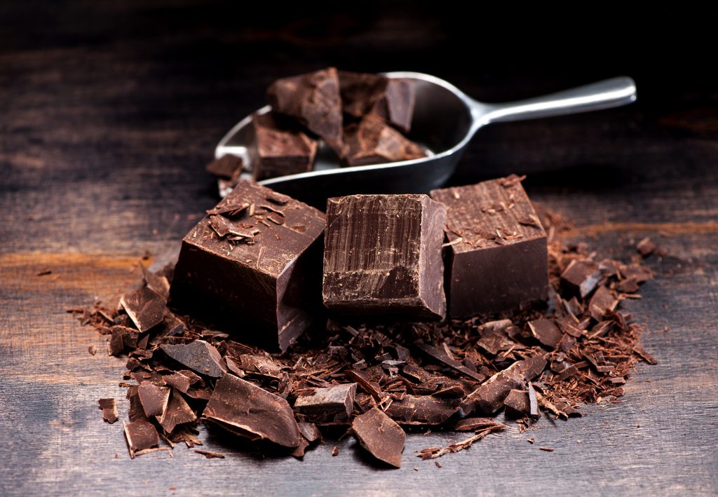 Pieces and chopped chocolate on a dark wooden background