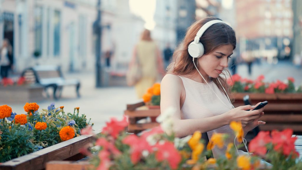Young girl listening to music on headphones outdoors